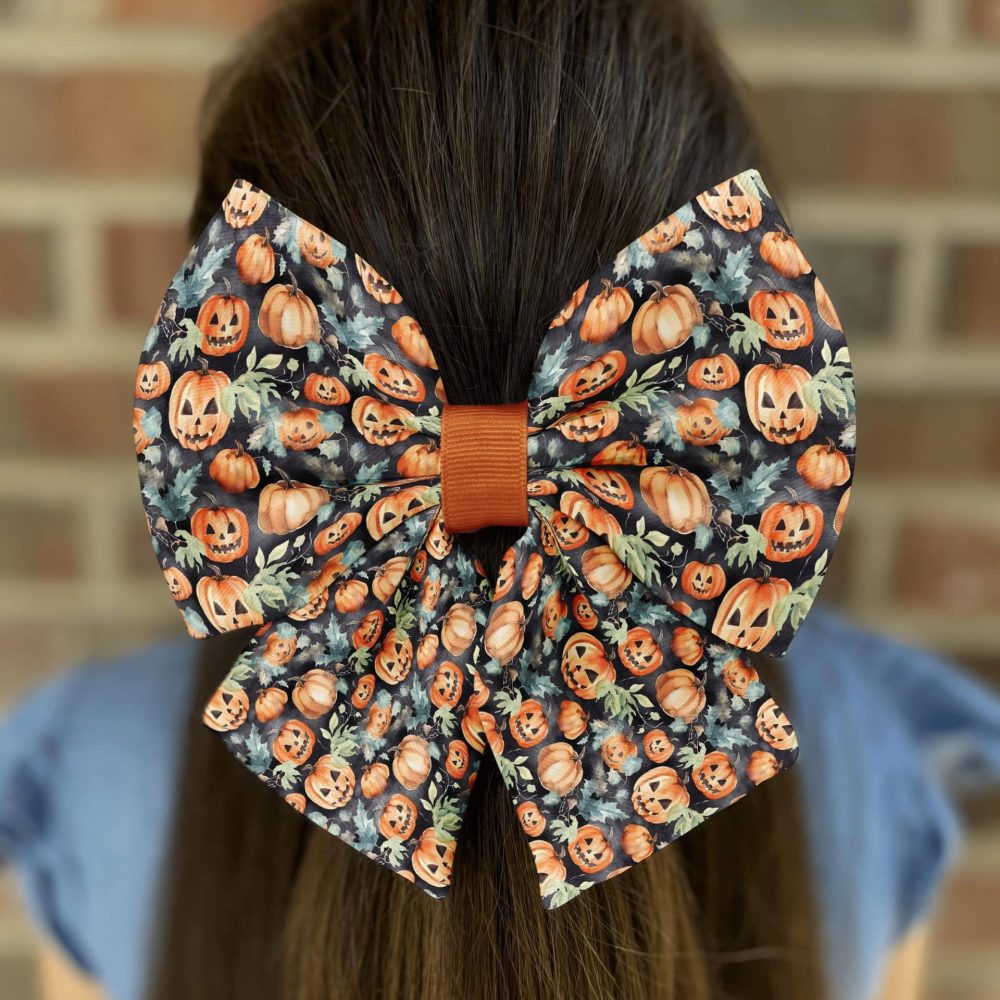 Pumpkin-themed hair bow on long brown hair.