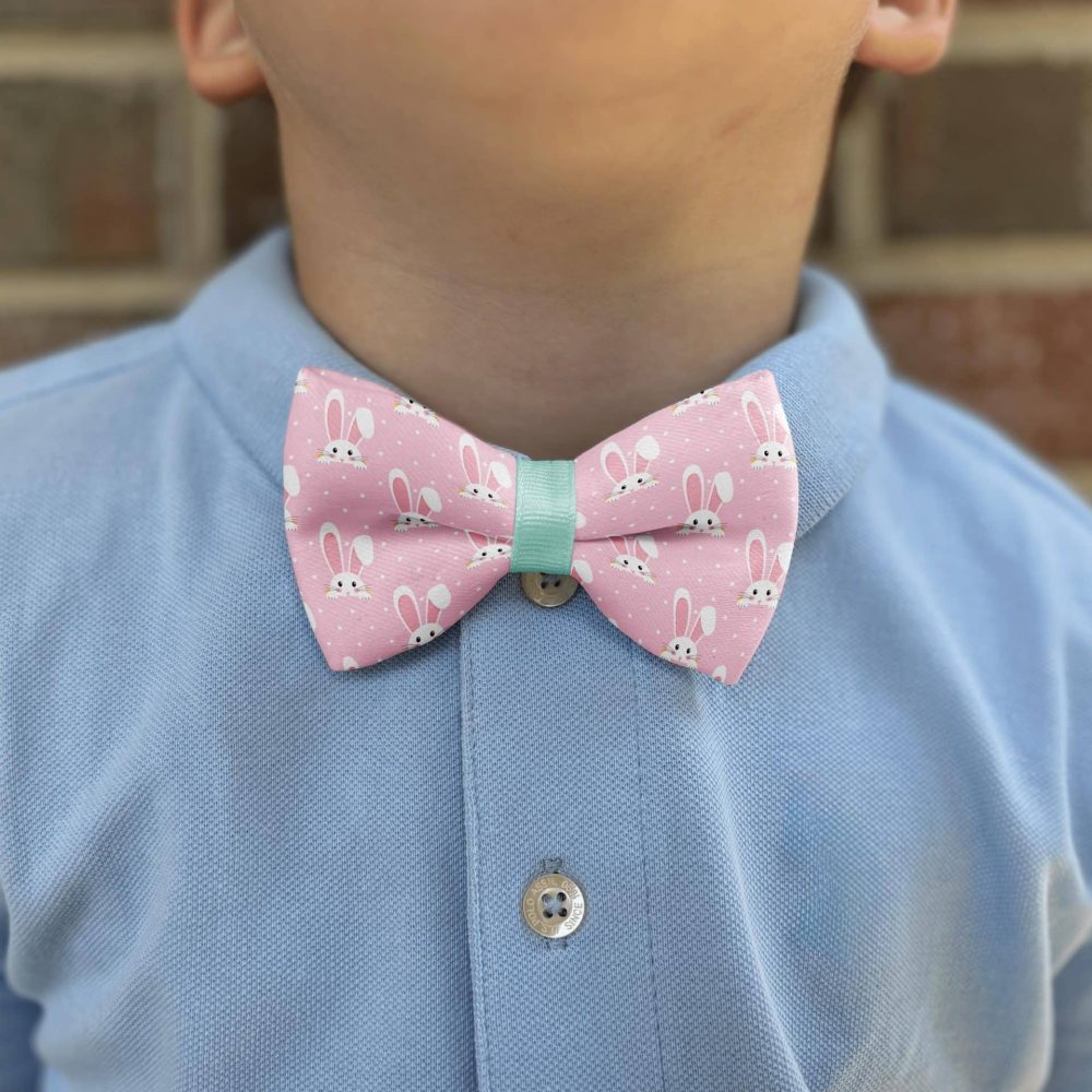 Child wearing bunny-patterned bow tie on blue shirt.