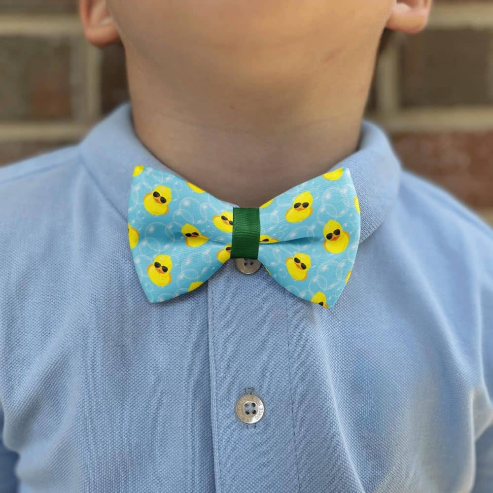 Child wearing duck-patterned bow tie and blue shirt.
