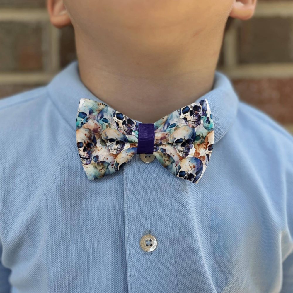 Child wearing skull-patterned bow tie and blue shirt.