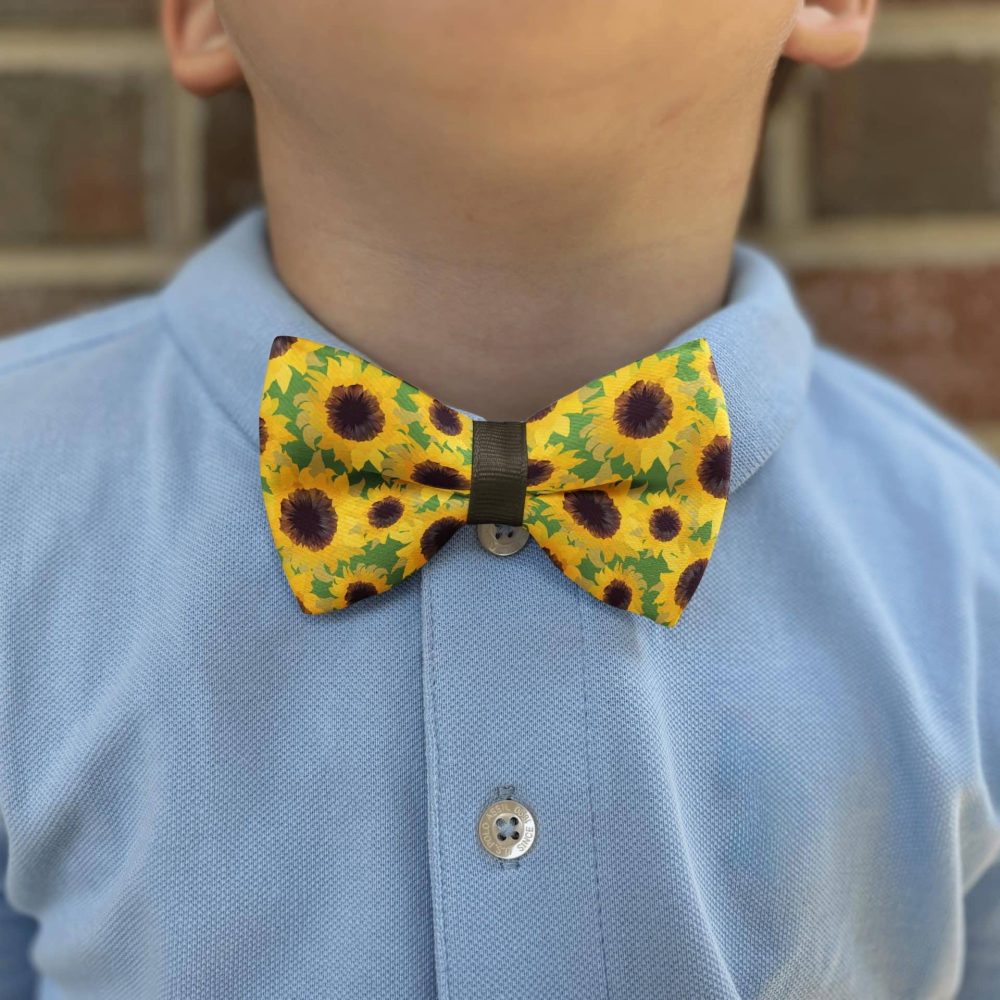 Child wearing sunflower patterned bow tie and blue shirt.