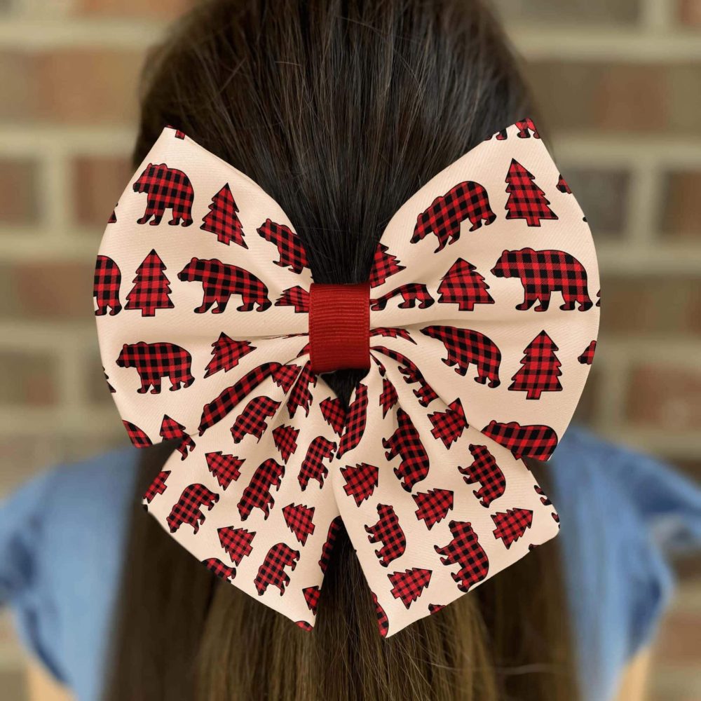 Red plaid bow with bear and tree pattern.