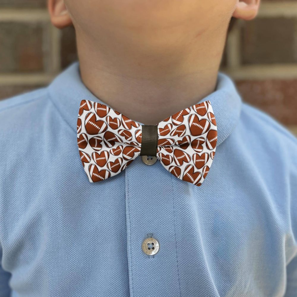 Child wearing football-patterned bow tie and blue shirt.