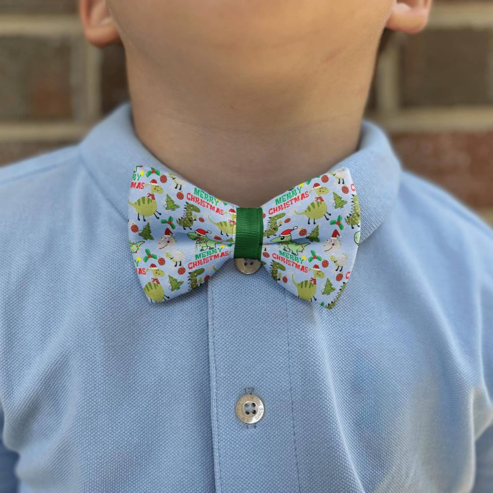 Child wearing Christmas-themed bow tie and blue shirt.