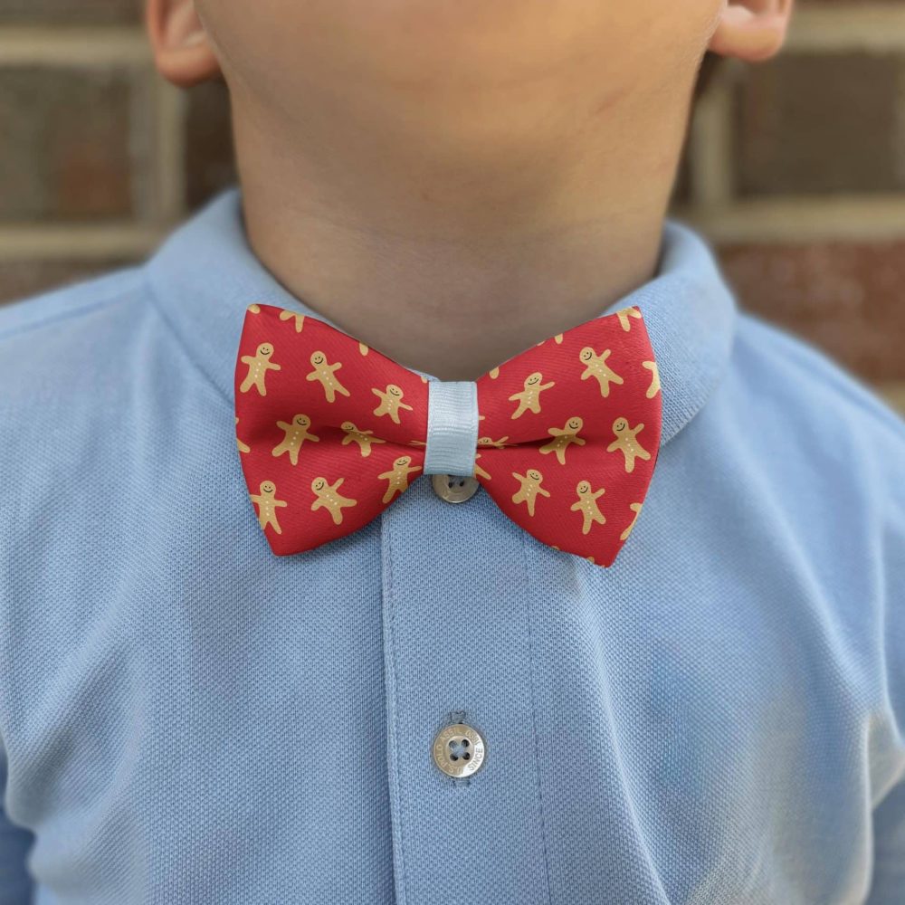 Child wearing gingerbread pattern bow tie and blue shirt.