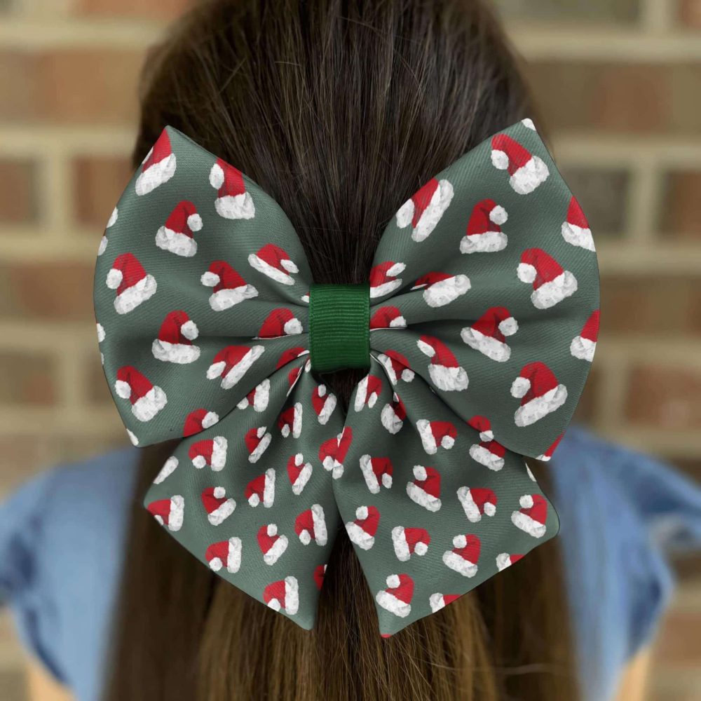 Girl wearing Christmas Santa hat patterned hair bow.