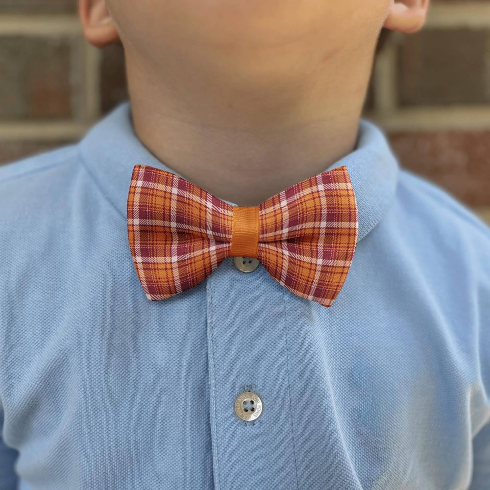 Child wearing plaid bow tie and blue shirt.