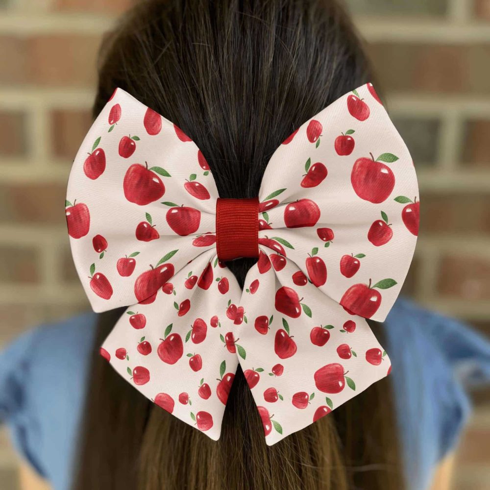 Hair bow with red apples pattern on ponytail.