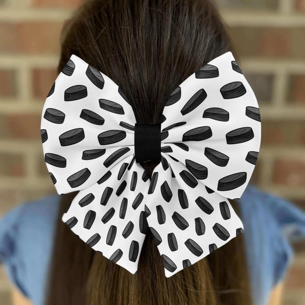 White bow with black ovals on brown hair.