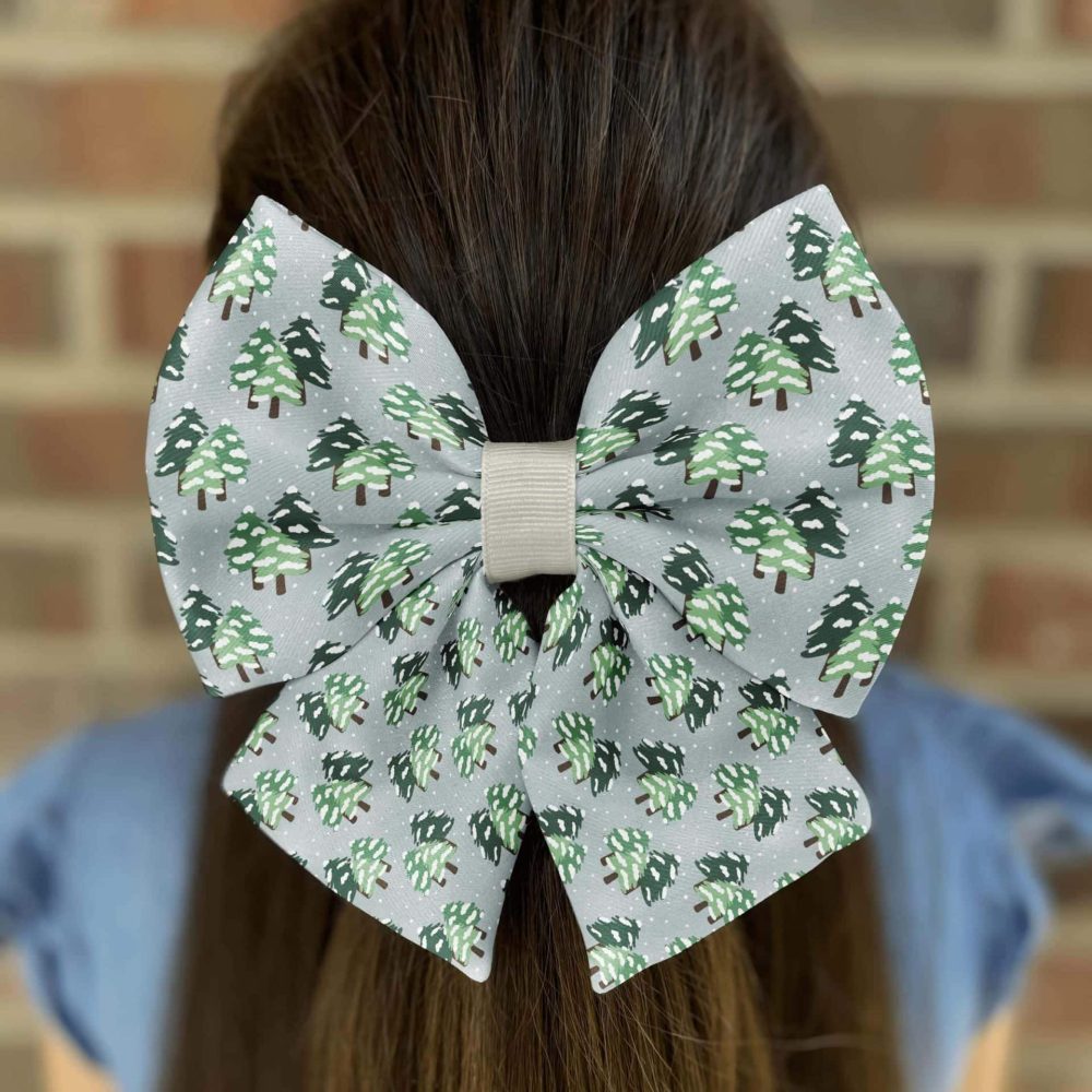 Girl wearing bow with Christmas tree pattern.